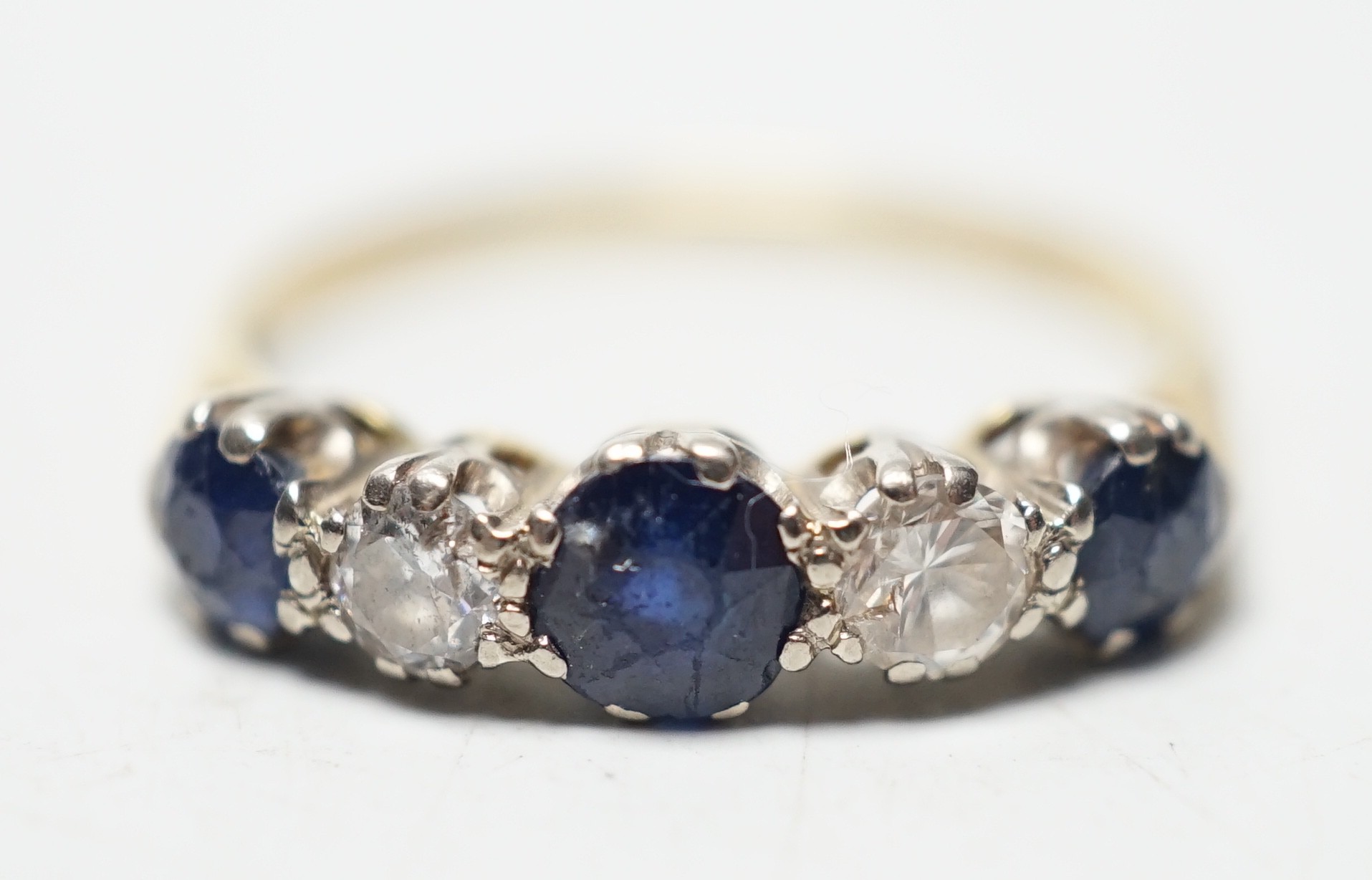 A modern 18ct gold, three stone sapphire and two stone diamond set half hoop ring, size R, gross weight 3.1 grams.